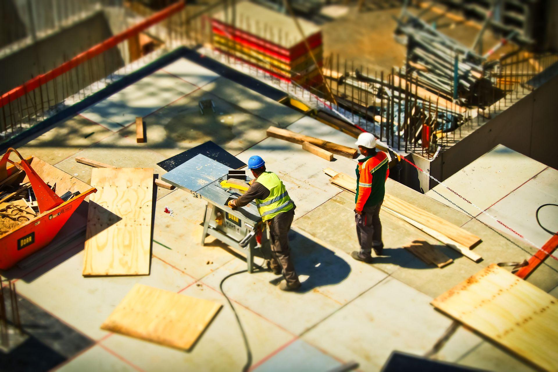 Construction workers engaging in tasks at an outdoor building site with safety hats and equipment