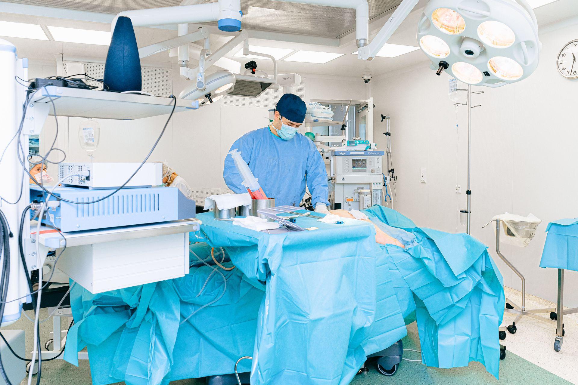 Doctor in surgical attire performing operation in a well-equipped operating room