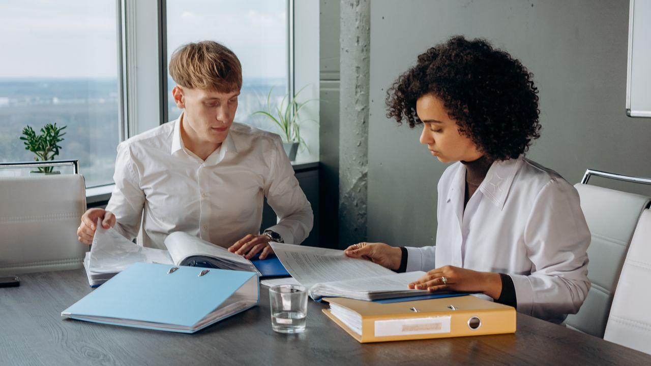 A Health and Safety consultant reviewing workplace documents with a manager